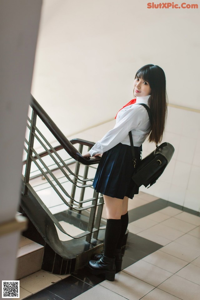 A woman in a school uniform is standing on the stairs.