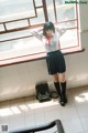 A woman in a school uniform leaning against a window.