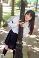 A woman in a school uniform leaning against a lamp post.