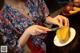 A woman cutting a mango with a knife.