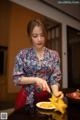 A woman in a red apron preparing food on a table.