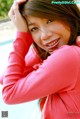 A woman in a pink shirt leaning against a swimming pool.