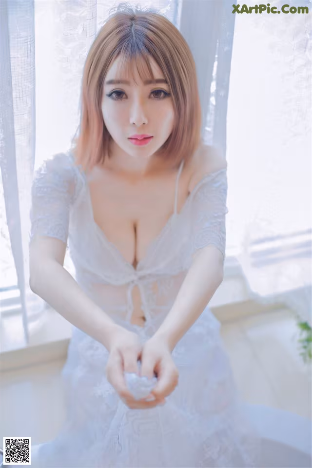 A woman in a white dress sitting on a window sill.