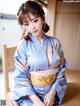 A woman in a blue kimono sitting on a wooden bench.