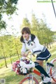 A woman riding a bike with a basket full of flowers.