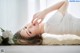 A woman laying on the floor with her hands on her face.