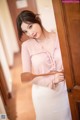 A woman in a pink blouse holding a wooden spoon.