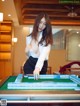 A woman in a white shirt and black skirt playing a game of mahjong.