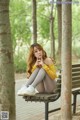 A woman sitting on a bench in a park.