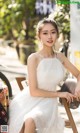 A woman in a white dress sitting on a chair.