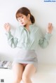 a woman in a green shirt and skirt sitting on a table