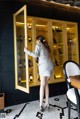 A woman standing in front of a glass cabinet filled with bottles of wine.