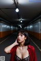 A woman in a red shirt is standing in a tunnel.