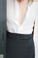 A woman wearing a white shirt and black skirt.