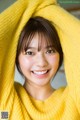 A woman in a yellow sweater smiles at the camera.