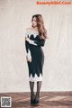 A woman in a black and white dress standing on a wooden floor.