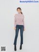 a woman in a pink sweater and jeans posing for a picture