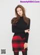 a woman in a black sweater and red plaid skirt