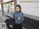 a woman in a blue top and black pants is walking down the street