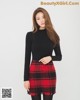 a woman in a black top and red plaid skirt