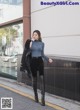 A woman in a blue top and black pants is walking down the street.