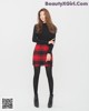 a woman in a black top and red plaid skirt