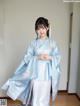 A woman in a blue kimono standing in a room.