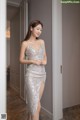 A woman in a silver dress standing in a hallway.