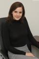 A woman sitting in a chair wearing a black turtle neck sweater.