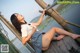 A woman in a school uniform is sitting on a wooden dock.