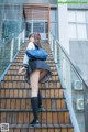 A woman in a school uniform is walking up some stairs.