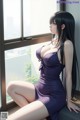 A woman in a purple dress sitting by a window.