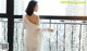 A woman in a white dress standing on a balcony.