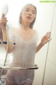 A woman standing in a shower holding a mirror.