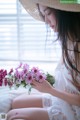 A woman sitting on a bed holding a bunch of flowers.