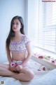 A woman sitting on a bed holding a flower.