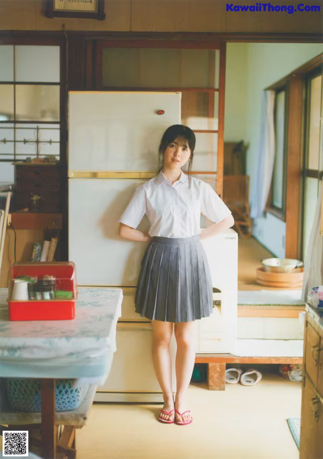 A woman standing in a kitchen next to a refrigerator.