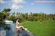 A woman in a bikini sitting on the edge of a pool.