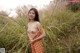 A woman in an orange polka dot dress standing in tall grass.