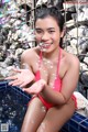 A woman in a pink bikini sitting in a pool with soap bubbles.