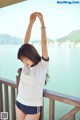 A woman in a white shirt and blue shorts standing on a balcony.