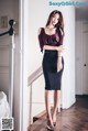 A woman in a black dress standing on a wooden floor.