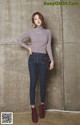 A woman standing in front of a concrete wall.