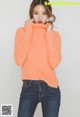 a woman wearing an orange sweater and jeans