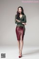 A woman in a green sweater and red leather skirt.