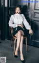 A woman sitting on a chair in front of a black door.