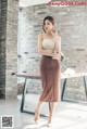 A woman standing in front of a table wearing a brown skirt.