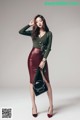 A woman in a green sweater and red leather skirt posing for a picture.