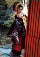 A woman in a kimono standing in front of a red door.